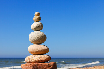 Zen pyramid of balanced stones on a background of the summer sea and blue sky