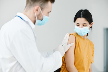 caring doctor injects covid-19 vaccine into female patient's shoulder vaccination