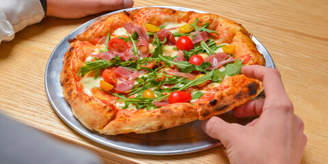 Young man eating a slice of pizza margherita. Still life, eating out concept. At restaurant or at home, pizza delivery.