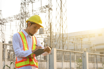 Engineers are reviewing and taking notes of electrical operation reports.