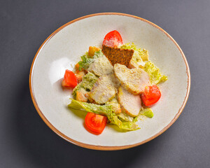 Bowl of Caesar Salad served on a black background in restaurant or diner. Traditional Caesar recipe