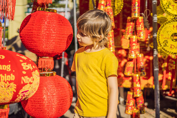 Fototapeta premium Caucasian tourist boy in Tet holidays. Vietnam Chinese Lunar New Year in springtime. TEXT TRANSLATION from Vietnamese: Congratulations on the Vietnamese, Chinese New Years and wishes of all the best