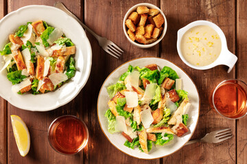 Caesar salad, overhead flat lay shot with croutons, sauce and wine on a dark rustic wooden background