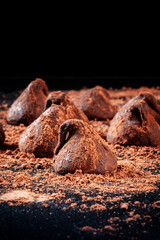 Many chocolate truffles on a black background with a place for text