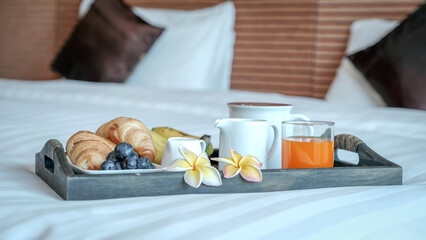 Breakfast in a tray on the bed in the luxury hotel room ready for tourist travel