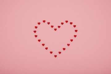 Valentine's Day heart shape made of small red hearts on pink background