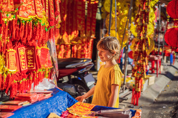 Obraz na płótnie Canvas Caucasian tourist boy in Tet holidays. Vietnam Chinese Lunar New Year in springtime. TEXT TRANSLATION from Vietnamese: Congratulations on the Vietnamese, Chinese New Years and wishes of all the best