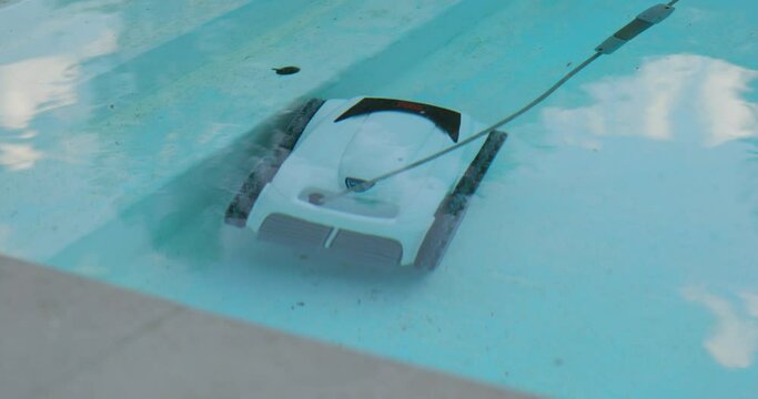 Electric Pool Cleaning Robot Cleans Steps of Swimming Pool with Clear Reflective Water Surface. Underwater Vacuum Robot in Operation with Chlorine Filter Treatment and Purification during Summertime.