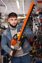 Portrait of man with an electric brush cutter in hardware store.