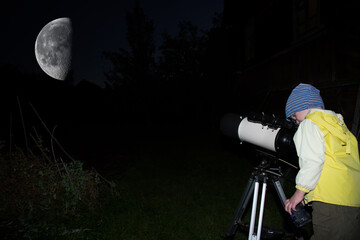 A child is watching the moon through a telescope.