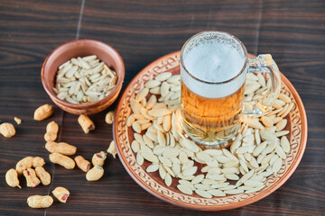 Obraz na płótnie Canvas Sunflower seeds, peanuts and a glass of beer on wooden table