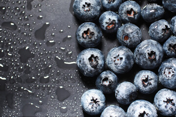Water drops on ripe sweet blueberry. Fresh blueberries background with copy space for your text. Vegan and vegetarian concept. Macro texture of blueberry berries.