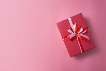 Red gift box with white bow on pink background top view, Valentines day, Flat lay style with copy space.