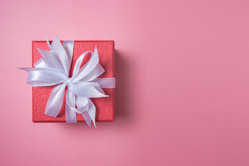 Red gift box with white bow on pink background top view, Valentines day, Flat lay style with copy space.