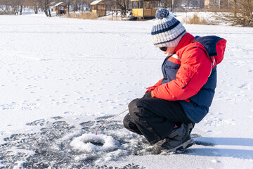 Fototapeta na wymiar Boy enjoys winter fishing