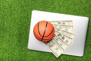 Obraz premium Money, laptop and ball for playing basketball on color background. Concept of sports bet