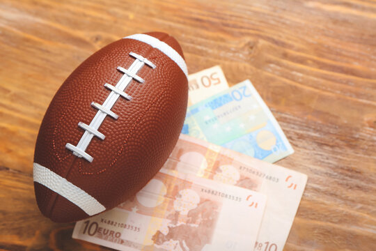 Money and rugby ball on wooden background. Concept of sports bet
