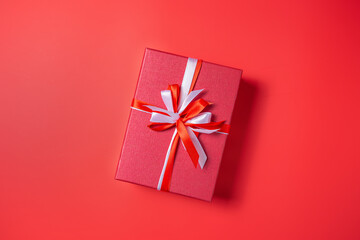 Red gift box with white and red bow on red background top view, Valentines day, Flat lay style with copy space.