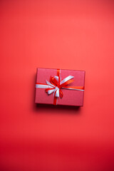 Red gift box with white and red bow on red background top view, Valentines day, Flat lay style with copy space.