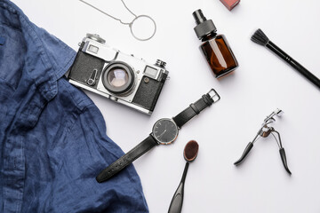 Stylish wristwatch, makeup accessories and photo camera on light background
