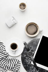 Obraz na płótnie Canvas Stylish wristwatch, cups of coffee and earphones on light background