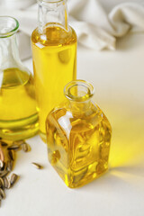 Bottles of oil and seeds on light background