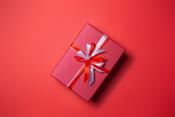 Red gift box with white and red bow on red background top view, Valentines day, Flat lay style with copy space.