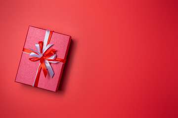 Red gift box with white and red bow on red background top view, Valentines day, Flat lay style with copy space.