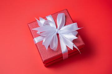 Red gift box with white and red bow on red background top view, Valentines day, Flat lay style with copy space.