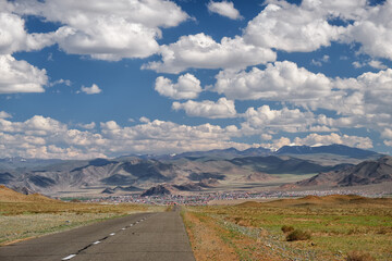 Empty Asphalt road in Mongolia  with mongolian town Bayan-Olgii (Bayan-Ulgii or Ulgii) on background