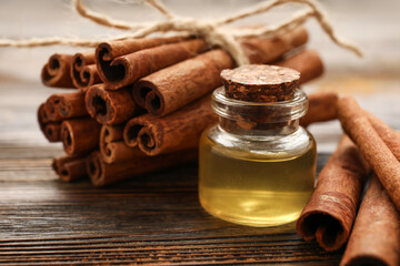 Cinnamon sticks and bottle of oil on wooden background