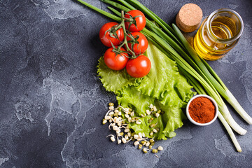 fresh salad greens vegetables seasonings and olive oil lie on the stone surface