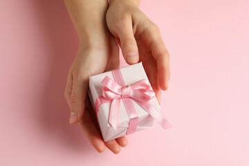 Female hands holding gift box on pink background
