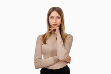 Pensive blond girl with thoughtful expression, keeps hand on chin, plans something or makes choice