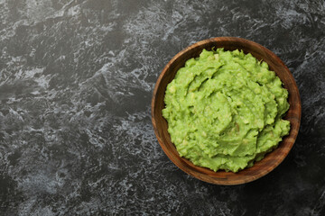 Bowl of guacamole on black smokey background, space for text