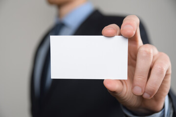 Businessman ,Business Man's hand hold showing business card - close up shot on grey background. Show a blank piece of paper. Paper visit card