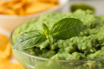 Glass bowl with guacamole and basil, close up
