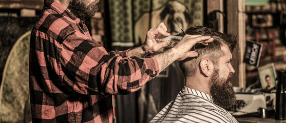 Fototapeta na wymiar Work in the barber shop. Man hairstylist. Hairdresser cutting hair of male client. Man visiting hairstylist in barbershop