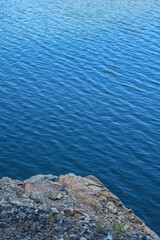 Stone rocks near water, on the background of lake, river, sea, ocean. Blue clear water. Artificial reservoirs