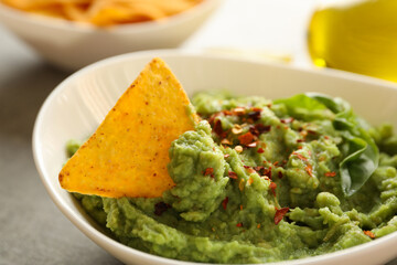 Bowl with guacamole, spices, basil and chip, close up