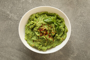 Bowl of guacamole on gray background, top view