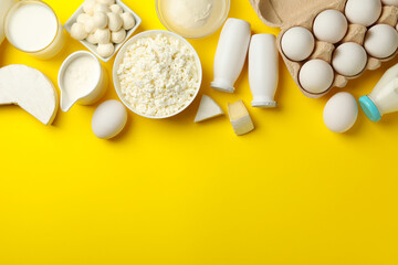 Different fresh dairy products on yellow background, top view