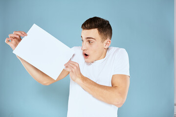 a man in a white t-shirt holds a sheet of paper copy space