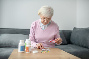 Senior woman with poor vision scrutinizing the medicines