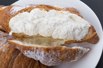 Tasty croissants with cream on black background.