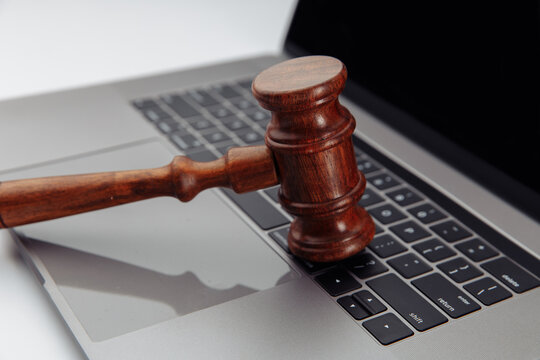 Judge's wooden gavel on laptop's keyboard. Close up.