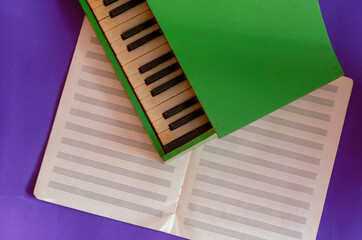 Green piano lies on top of an open music notebook on a blue background.
