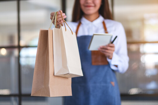 Closeup image of a female entrepreneur, waitress holding and giving shopping bag to customer