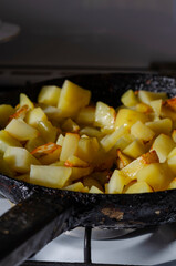 The process of cooking fried potatoes in a skillet on the kitchen stove.