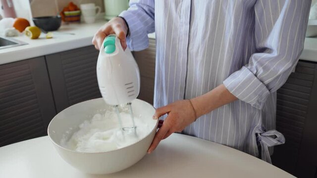 Mom whips the mixture in a bowl with an electric mixer. We prepare a cake for Easter